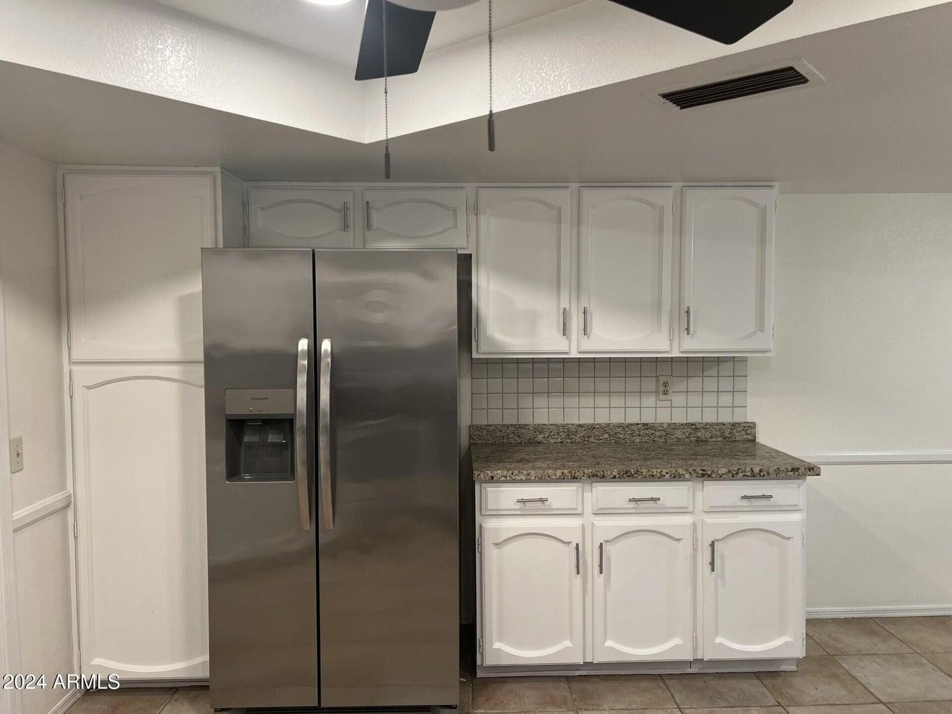 16623 North 29th Drive Phoenix, AZ 85053 - Photo 5 of 13 a kitchen with white cabinets and refrigerator