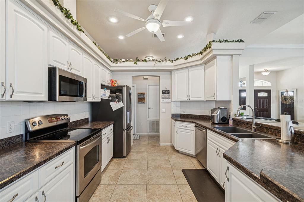 5287 Slater Road Spring Hill, FL 34608 - Photo 19 of 86 a kitchen with stainless steel appliances granite countertop a sink a stove top oven a chimney cabinets and a counter top space
