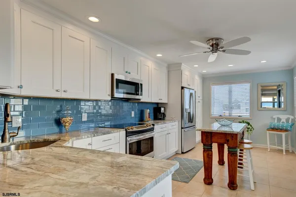 a kitchen with stainless steel appliances kitchen island granite countertop a refrigerator oven a sink a dining table and chairs with wooden floor