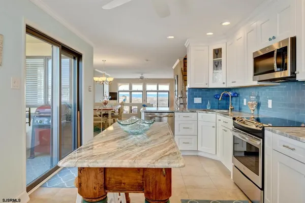 a kitchen with stainless steel appliances granite countertop a stove top oven a sink dishwasher a refrigerator and white cabinets with wooden floor