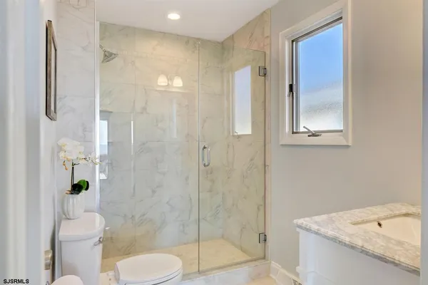 a bathroom with a granite countertop toilet a sink and shower