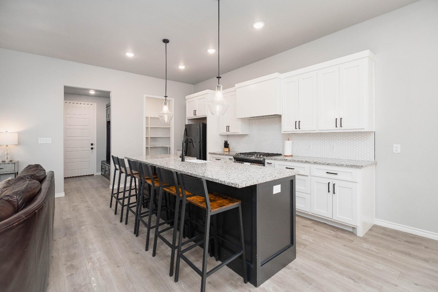 5921 Harvard Street Lubbock, TX 79416 - Photo 11 of 34 a kitchen with stainless steel appliances granite countertop a stove a sink a refrigerator a dining table and chairs with wooden floor