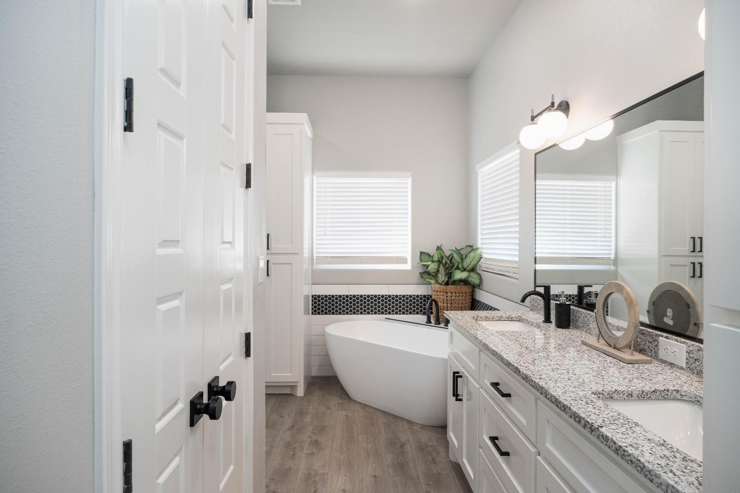 5921 Harvard Street Lubbock, TX 79416 - Photo 22 of 34 a bathroom with a double vanity sink a large mirror and a bathtub
