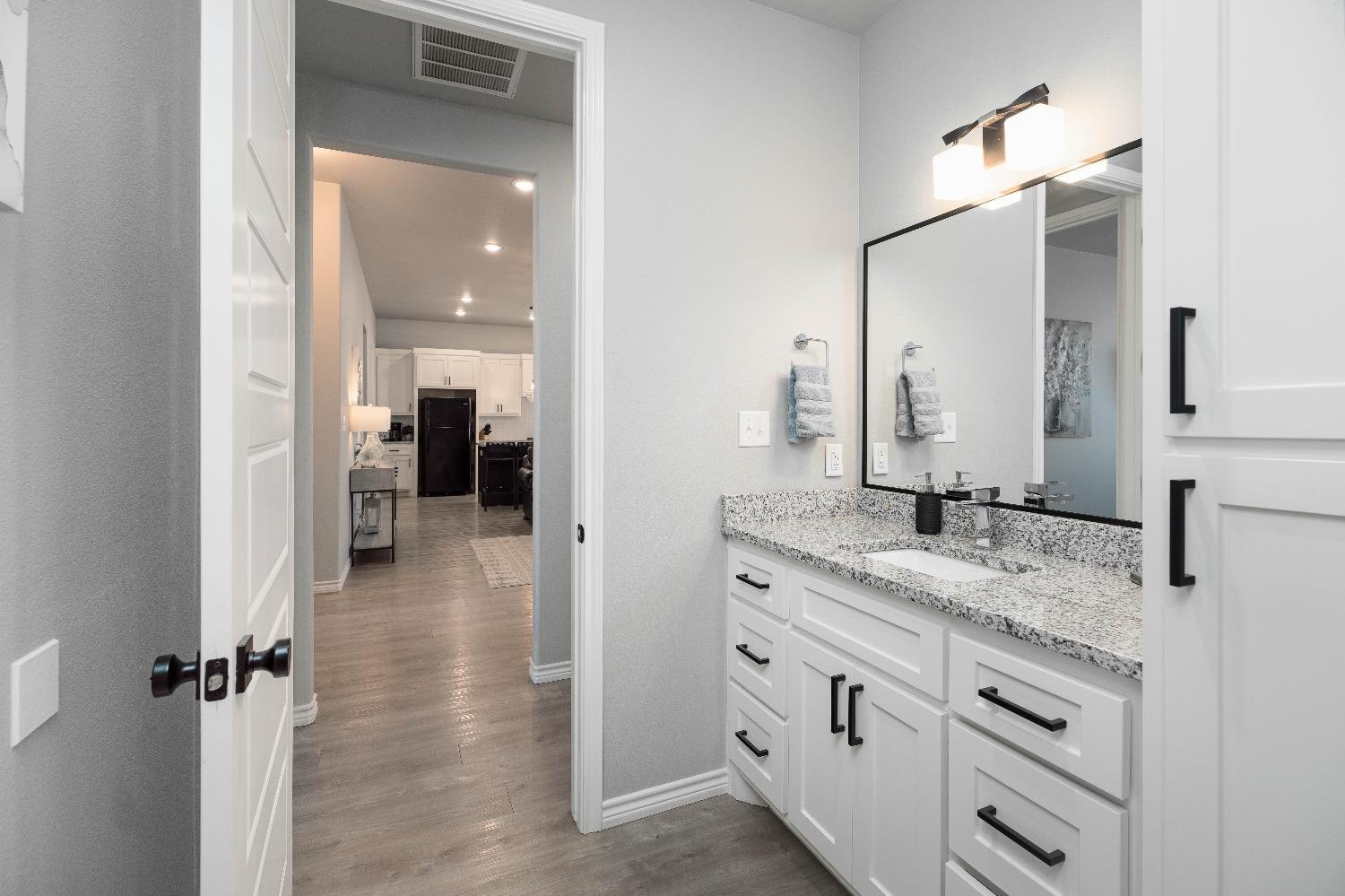5921 Harvard Street Lubbock, TX 79416 - Photo 29 of 34 a bathroom with a granite countertop sink vanity and mirror