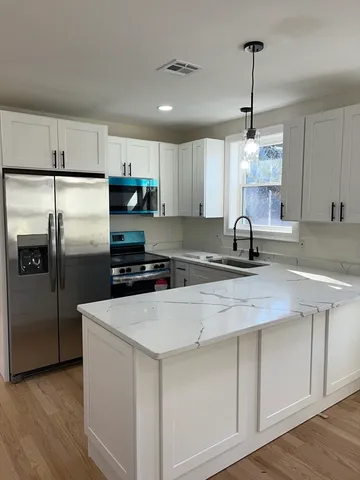 a kitchen with stainless steel appliances a sink a stove a refrigerator cabinets and wooden floor