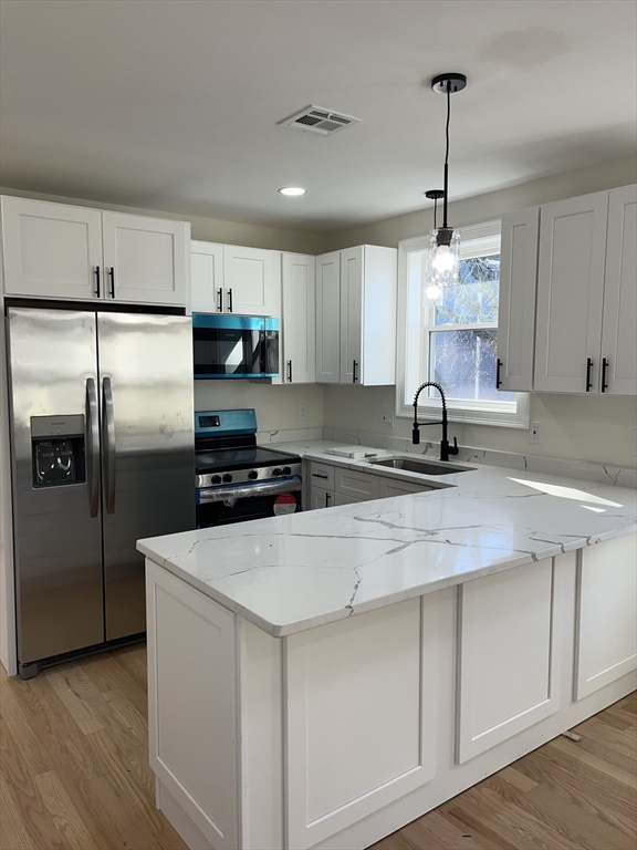 a kitchen with stainless steel appliances a sink a stove a refrigerator cabinets and wooden floor