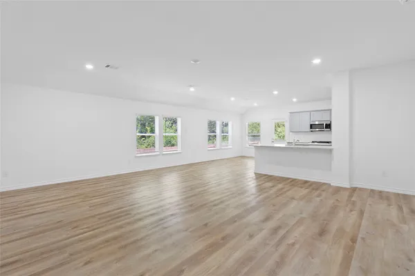 a view of an empty room with a window and wooden floor