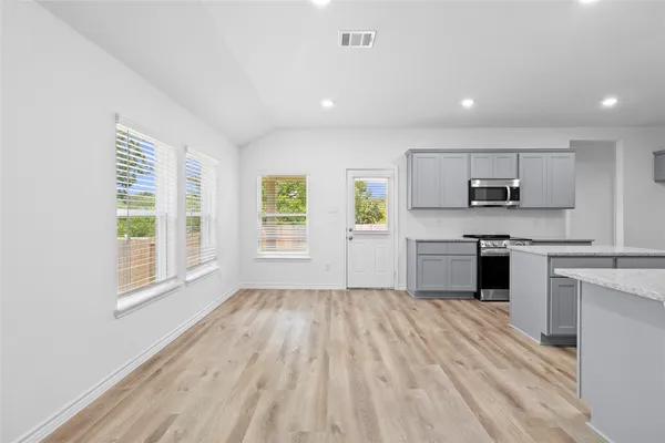 a kitchen with a refrigerator a stove top oven and white walls