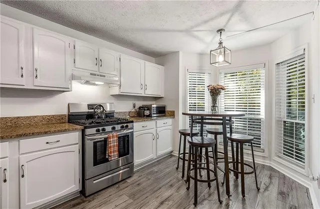 a kitchen with granite countertop white cabinets and white appliances