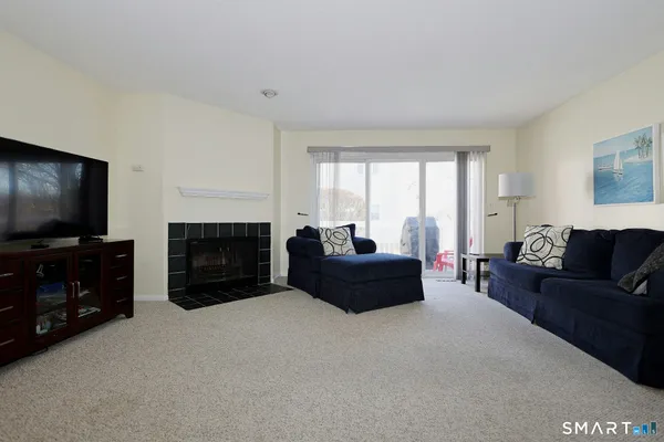 a living room with furniture a fireplace a flat screen tv and a large window