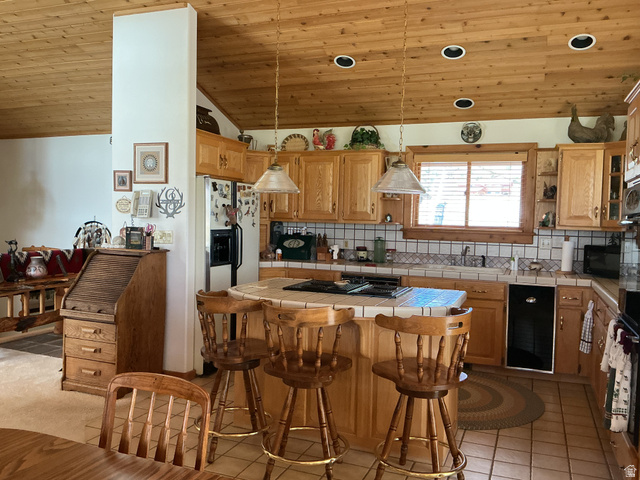 550 State Line Road Manila, UT 84046 - Photo 9 of 41 Kitchen featuring a wood-panel vaulted ceiling, recessed lighting, natural wood cabinetry, a tile countertop and backsplash, and a built-in kitchen island with seating