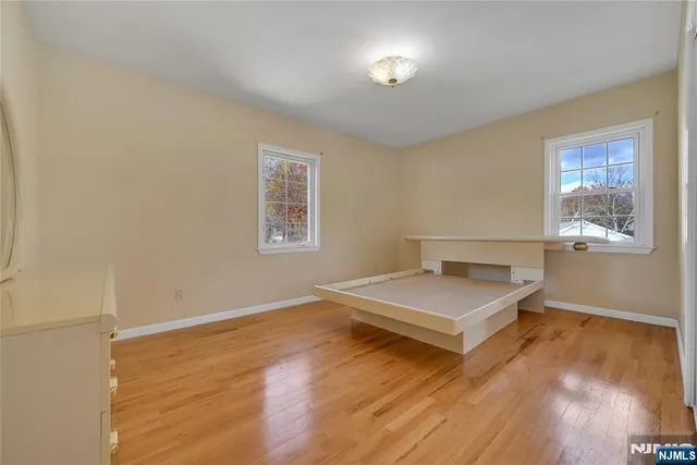 an empty room with mirror on dresser and a table
