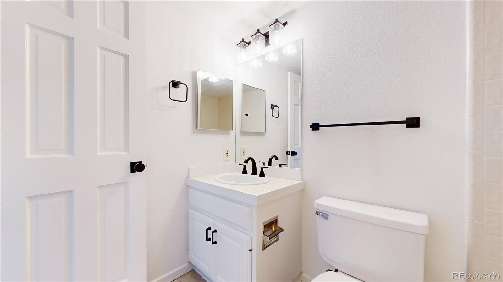 357 Harrison Street Denver, CO 80206 - Photo 24 of 40 a bathroom with a sink mirror toilet and vanity