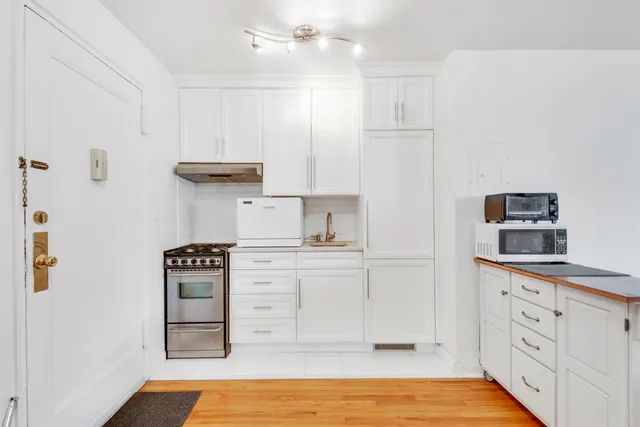 a kitchen with granite countertop a refrigerator cabinets and wooden floor
