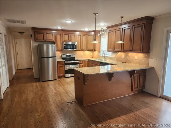 a kitchen with stainless steel appliances granite countertop a refrigerator a sink and a stove