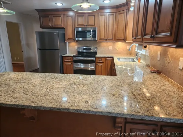 a kitchen with granite countertop a refrigerator oven a sink a stove and dishwasher