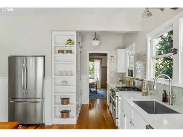 a kitchen with a refrigerator a sink and a stove with wooden floor