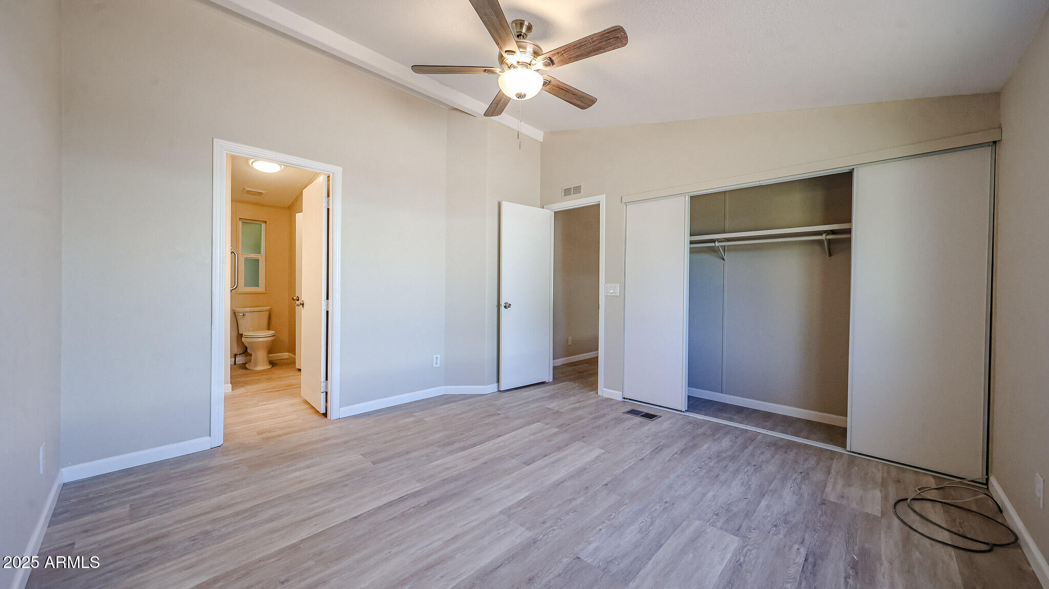 3901 East Pinnacle Peak Road, Unit 108 Phoenix, AZ 85050 - Photo 12 of 30 an empty room with wooden floor a ceiling fan and closet