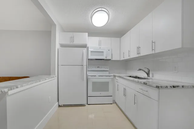 a kitchen with white cabinets and white appliances