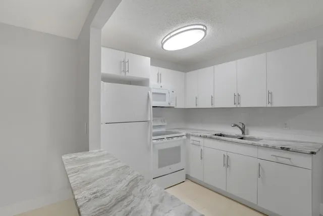 a kitchen with a sink dishwasher and white cabinets
