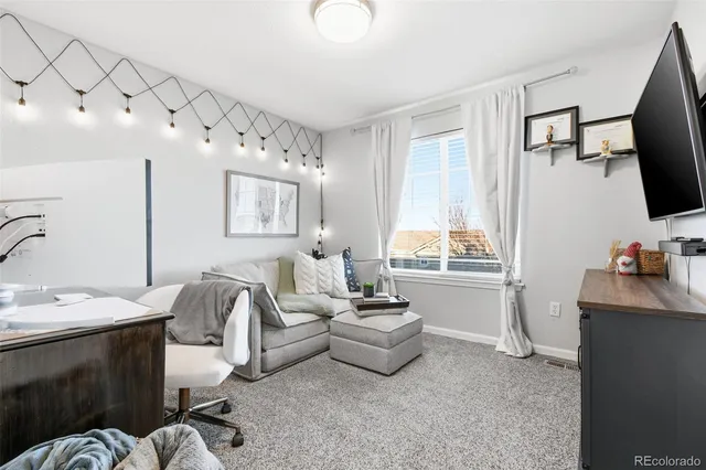 a living room with furniture a flat screen tv and a window
