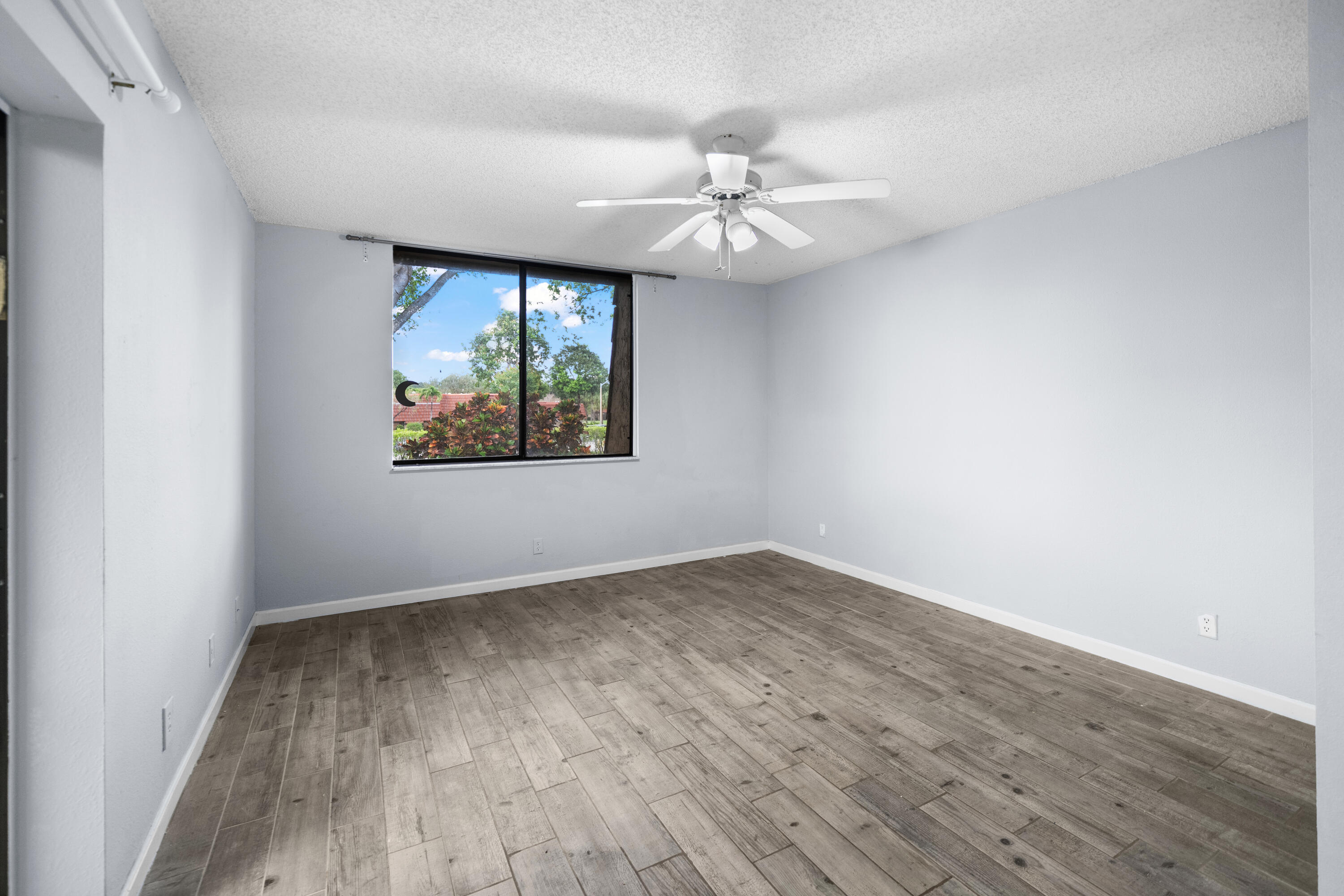 8237 Severn Drive, Unit A Boca Raton, FL 33433 - Photo 16 of 19 an empty room with wooden floor chandelier fan and windows