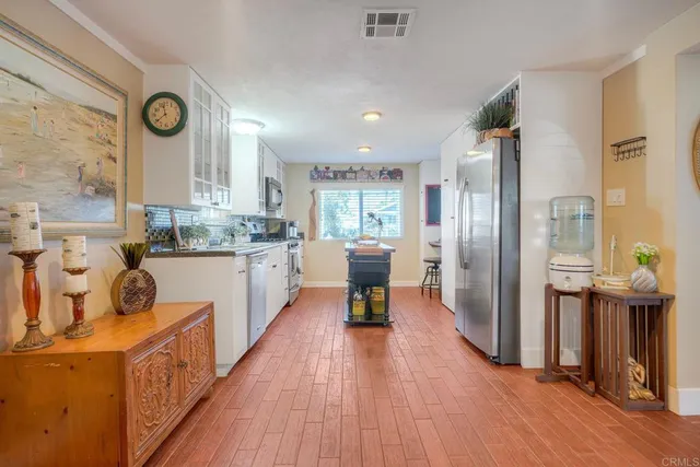 a kitchen with stainless steel appliances a refrigerator a sink dishwasher a stove and white countertops with wooden floor