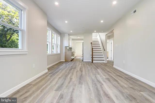 a view of empty room with wooden floor and fan