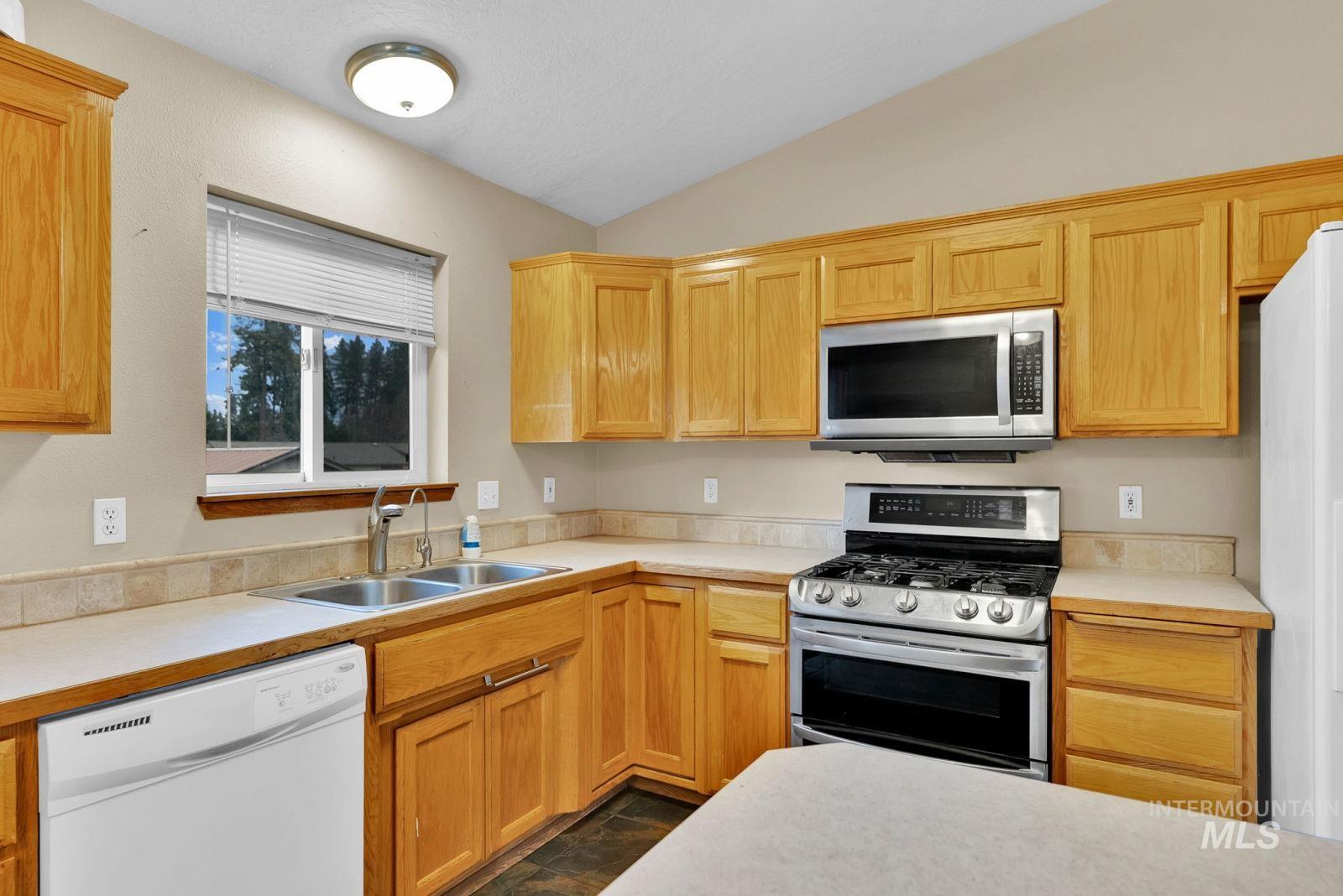 8561 Nebraska Street Rathdrum, ID 83858 - Photo 13 of 50 Kitchen featuring light countertops, stainless steel appliances, lofted ceiling, and light wood finish cabinetry