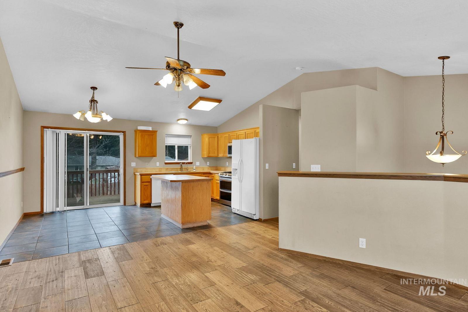 8561 Nebraska Street Rathdrum, ID 83858 - Photo 6 of 50 Kitchen with suspended lighting, light countertops, a center island, light wood finished floors, and white fridge with ice dispenser