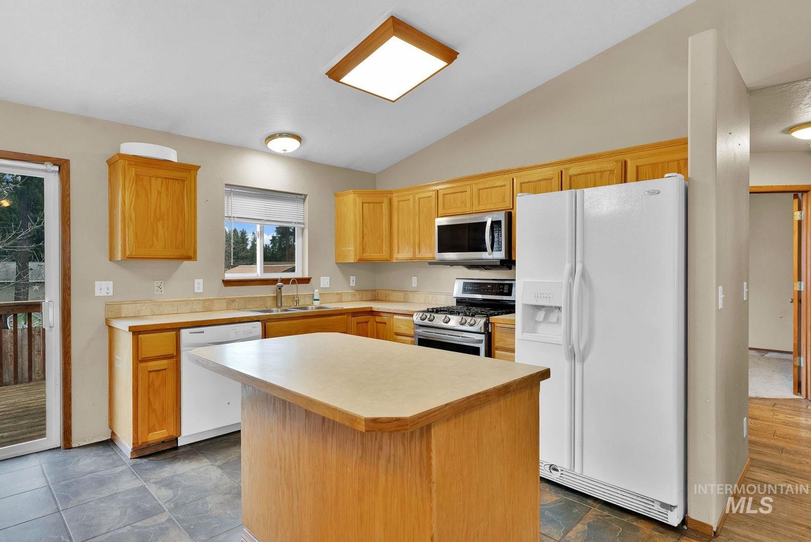8561 Nebraska Street Rathdrum, ID 83858 - Photo 9 of 50 Kitchen featuring stainless steel appliances, light countertops, vaulted ceiling, a center island, and light wood finish cabinetry