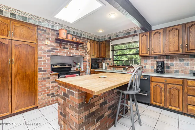 a kitchen with stainless steel appliances kitchen island granite countertop a refrigerator oven a sink dishwasher and white cabinets with wooden floor