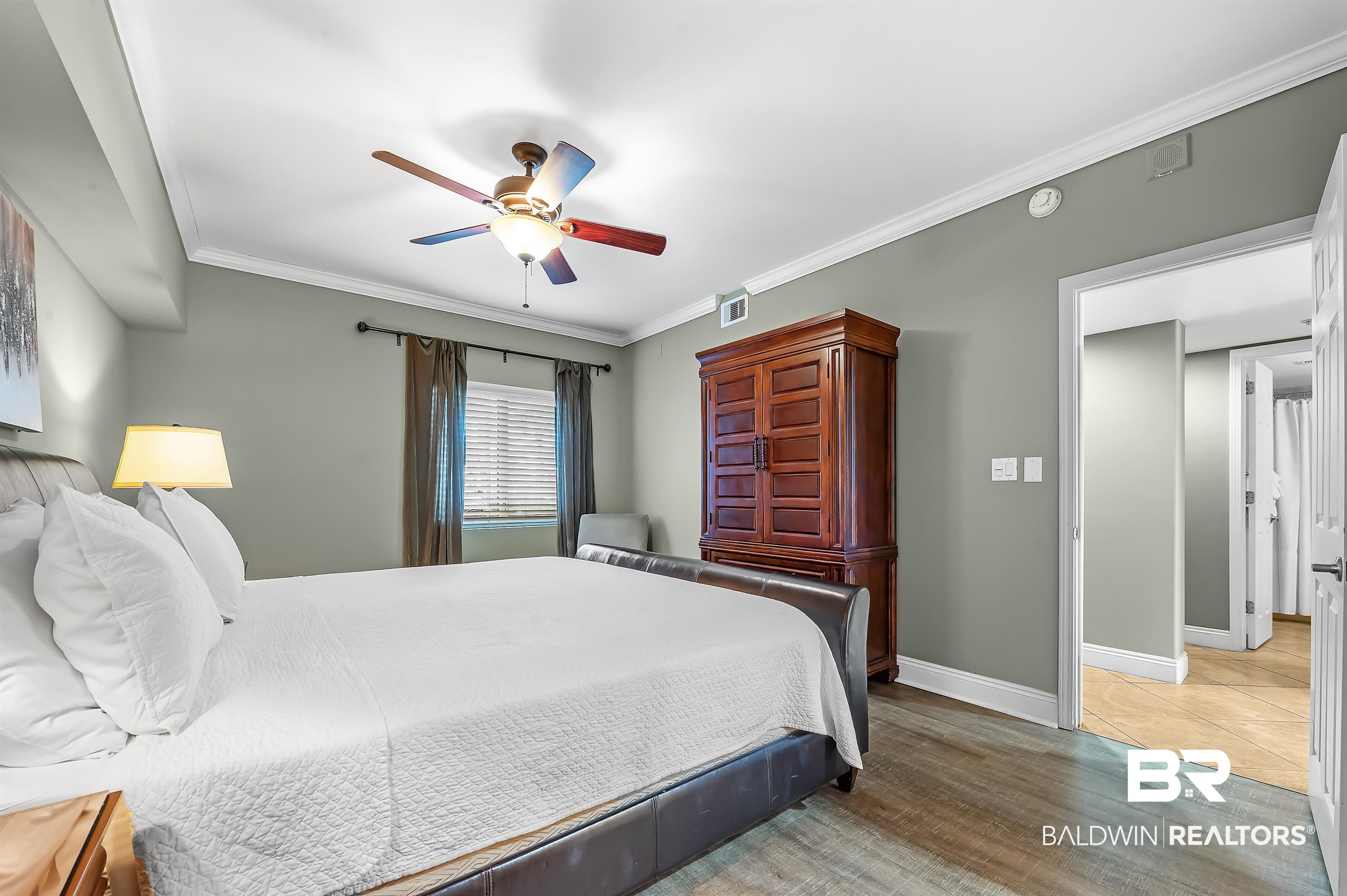 16287 Perdido Key Drive, Unit 105 Pensacola, FL 32507 - Photo 27 of 66 Bedroom featuring wood-finish flooring, a ceiling fan with integrated lighting, crown molding, and a window with blinds