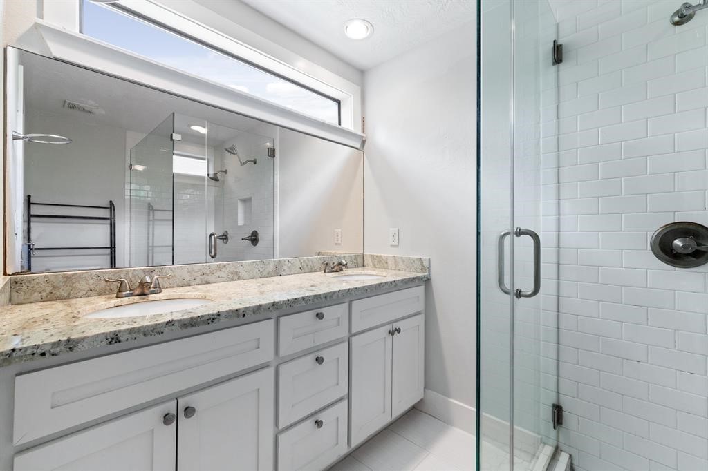 1305 Idylwild Street Houston, TX 77009 - Photo 27 of 31 Modern bathroom with a large glass-enclosed shower featuring white subway tiles, a double-sink vanity with granite countertops, and ample natural light from a high window.