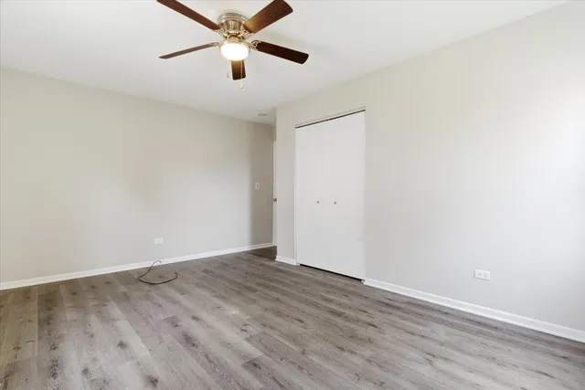 an empty room with wooden floor and a ceiling fan