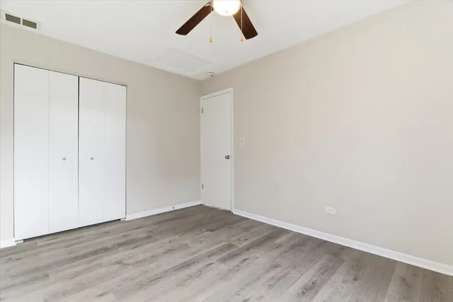 an empty room with a ceiling fan and wooden floor