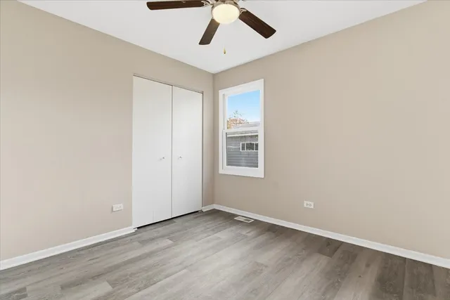 an empty room with a ceiling fan and wooden floor
