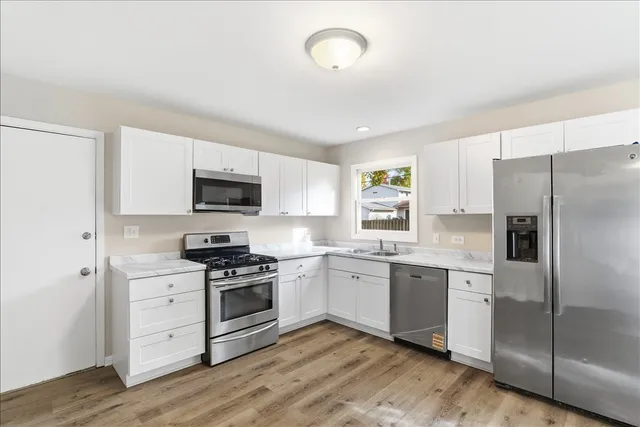 a kitchen with a sink a microwave a refrigerator and white cabinets