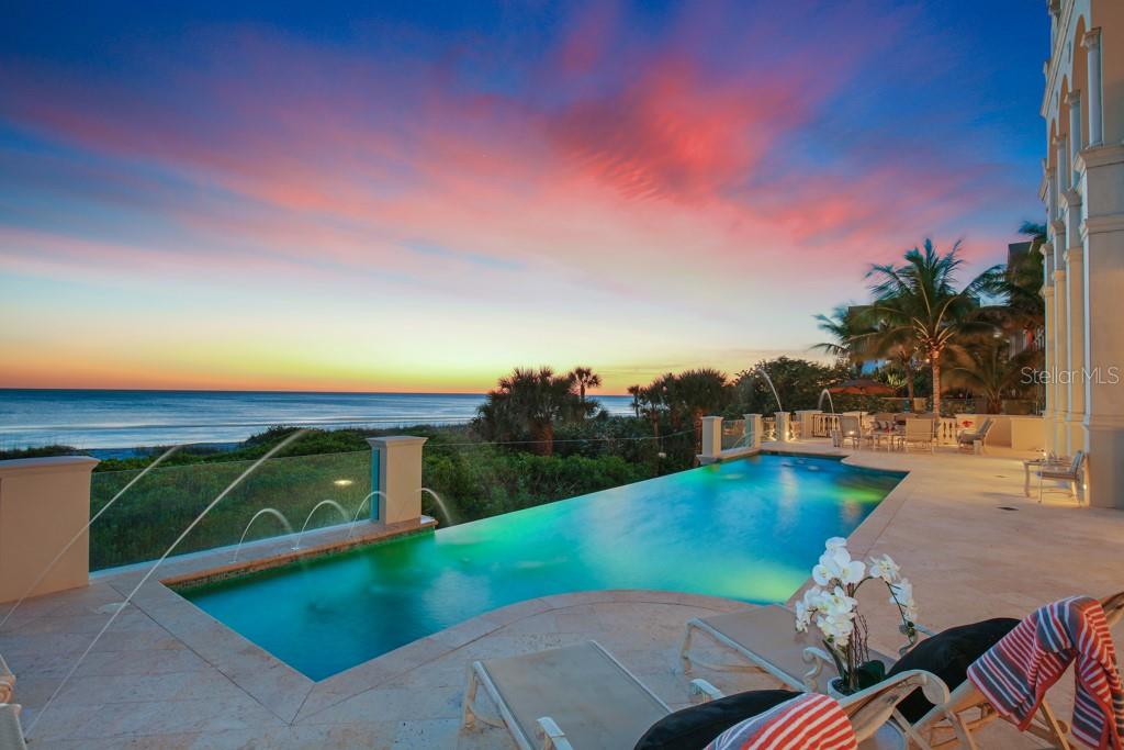 a view of a swimming pool with lawn chairs under an umbrella