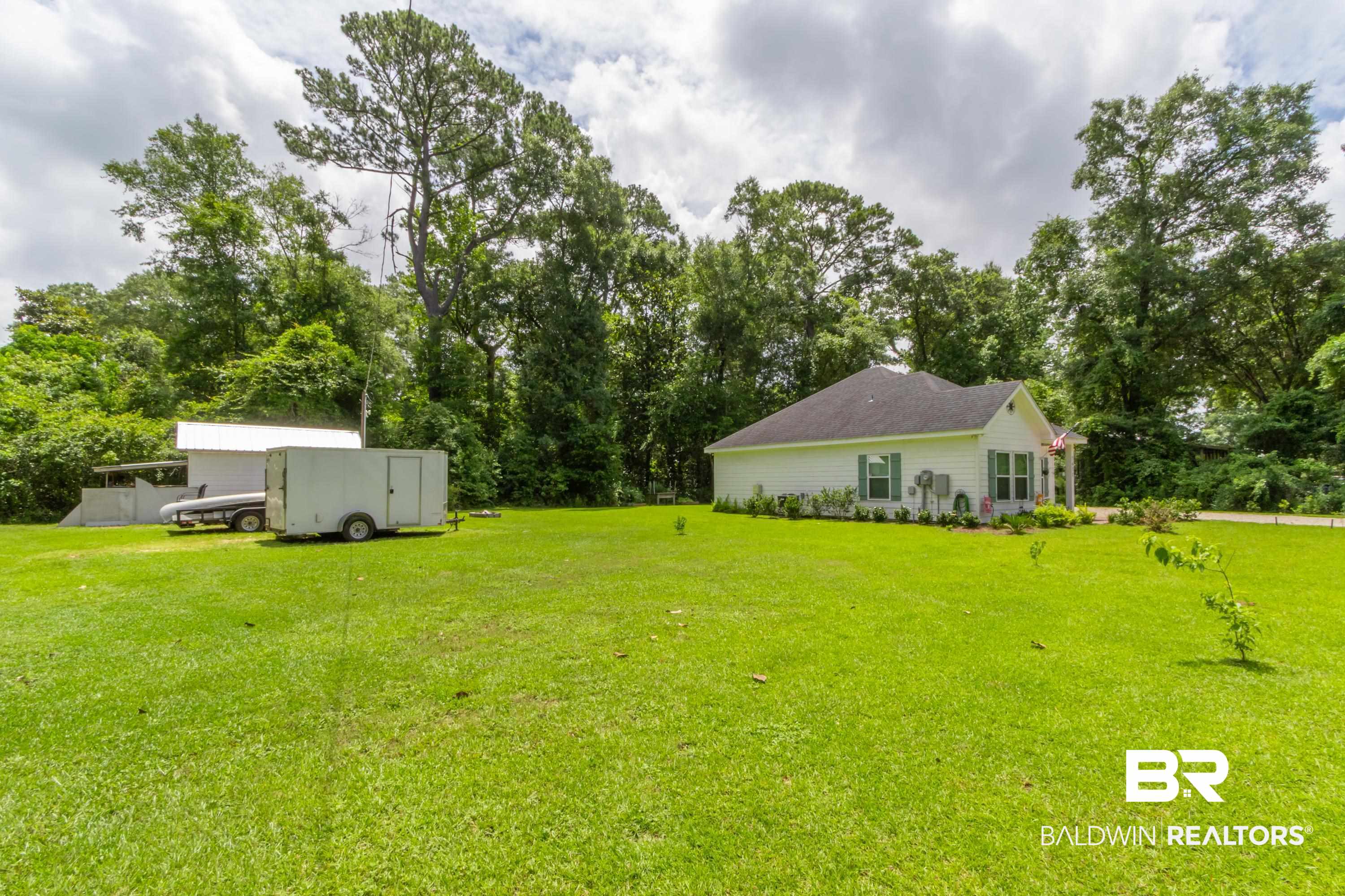 7472 Coopers Landing Road Foley, AL 36535 - Photo 30 of 40 Expansive front lawn with a white single-story residence featuring a dark roof, white siding, and green window shutters