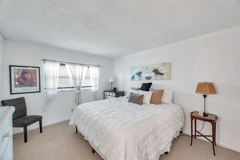 1430 Heather Ridge Boulevard, Unit 304 Dunedin, FL 34698 - Photo 15 of 36 a bedroom with a bed a chair and a lamp on table