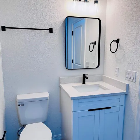 a bathroom with a toilet sink vanity and mirror