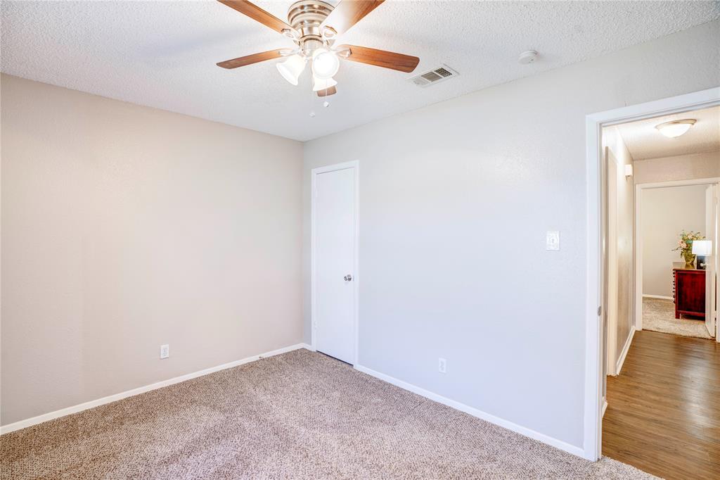6028 Ridgecrest Drive Watauga, TX 76148 - Photo 30 of 40 an empty room with a chandelier fan and wooden floor
