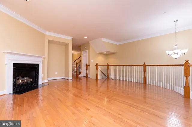 a view of an empty room with wooden floor a fireplace