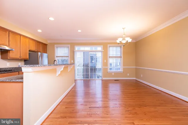 a view of a kitchen with kitchen island a sink wooden floor and a large window