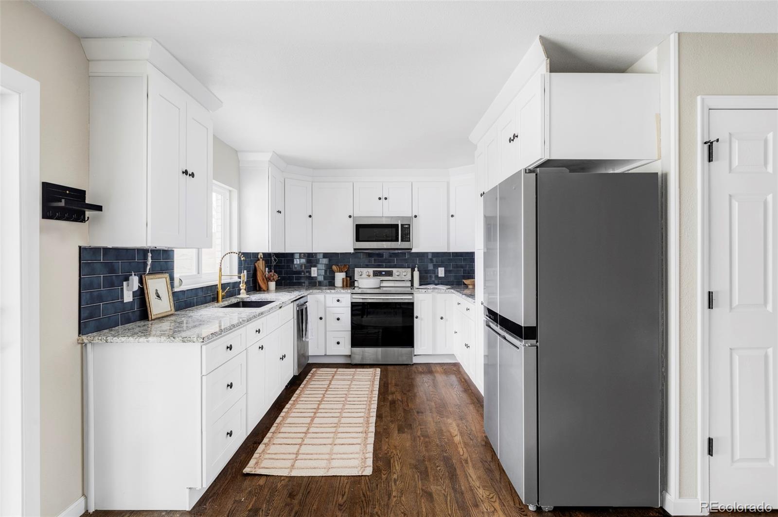 3406 South Stuart Street Denver, CO 80236 - Photo 12 of 34 a kitchen with granite countertop a refrigerator stove and sink
