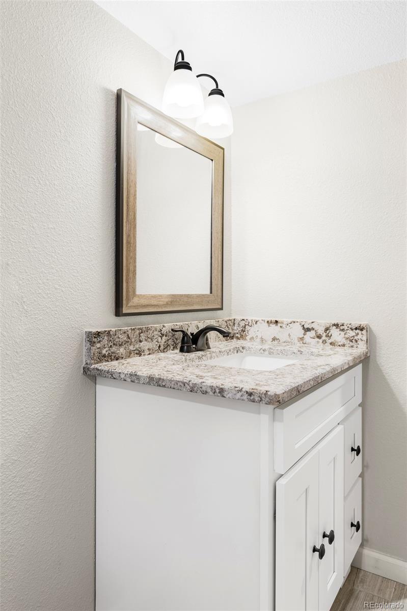 3406 South Stuart Street Denver, CO 80236 - Photo 25 of 34 a bathroom with a granite countertop sink and a mirror
