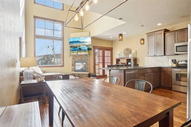 a open kitchen with stainless steel appliances granite countertop a stove a refrigerator a sink dishwasher a dining table and chairs with wooden floor