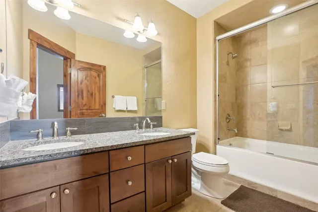 a bathroom with a granite countertop sink a toilet a mirror and shower