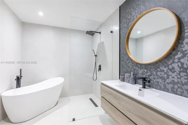 a bathroom with a white tub a mirror and vanity